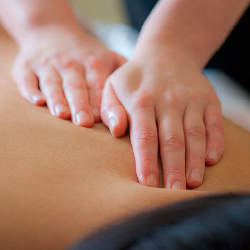 Dos manos apoyadas sobre una espalda y presionando suavemente, mientras se realiza un masaje.
