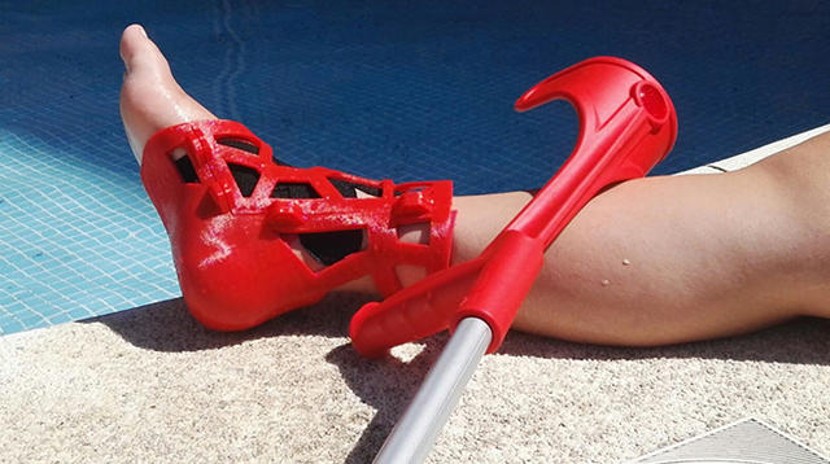 Una férula de color rojo impresa en 3D inmovilizando un tobillo.